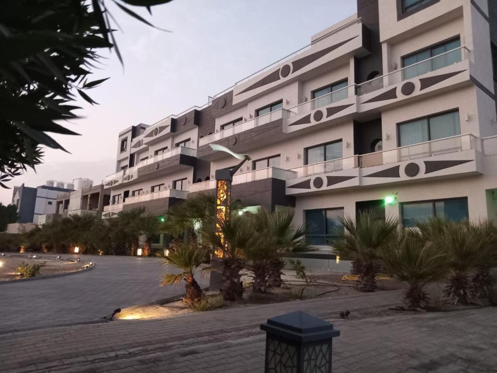 a large white building with palm trees in front of it at Al Salam Resort in Al Khīrān