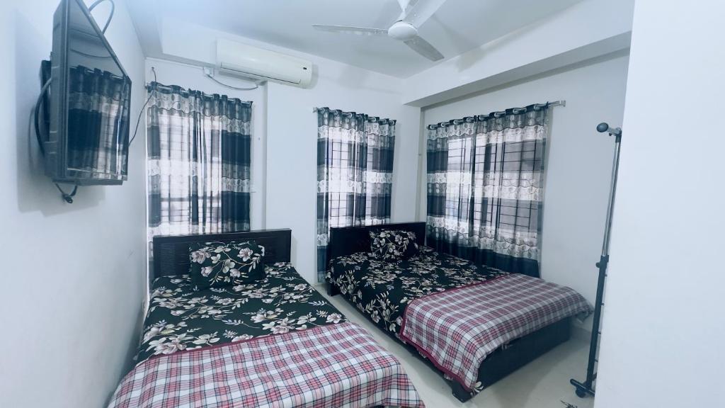 a bedroom with two beds and a tv and windows at Appayan Guest House (Baridhara) in Dhaka