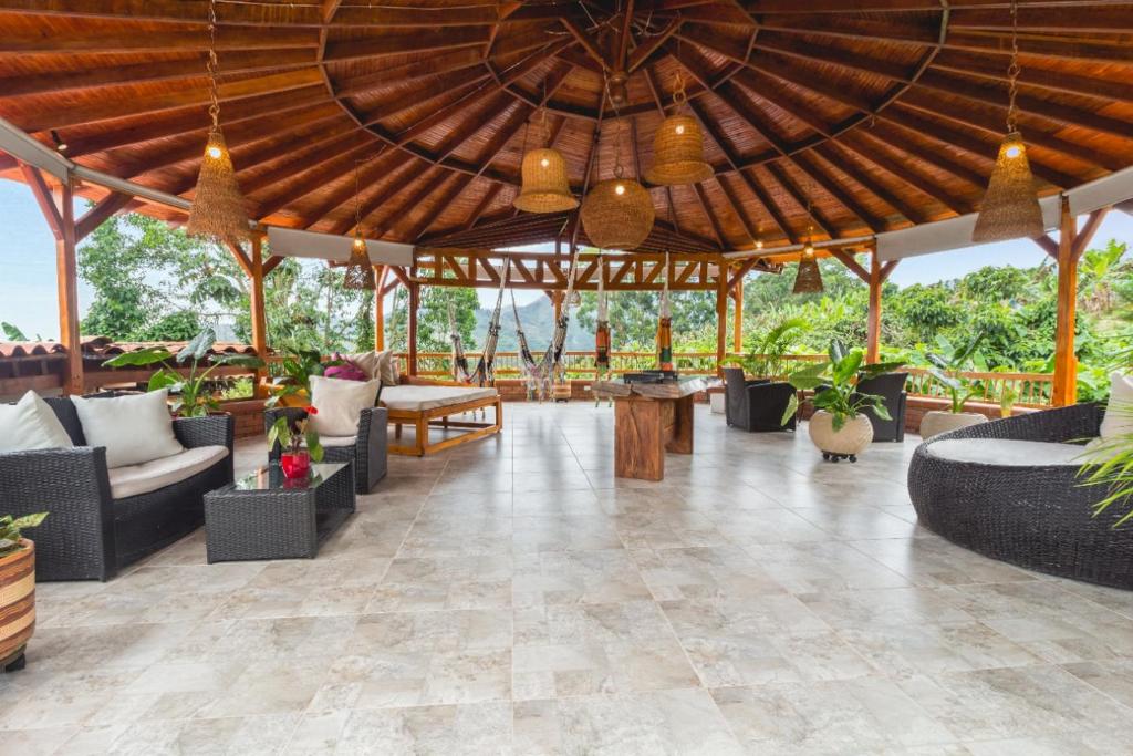a large wooden pavilion with couches and tables at Hotel Spa La Colina in Pereira