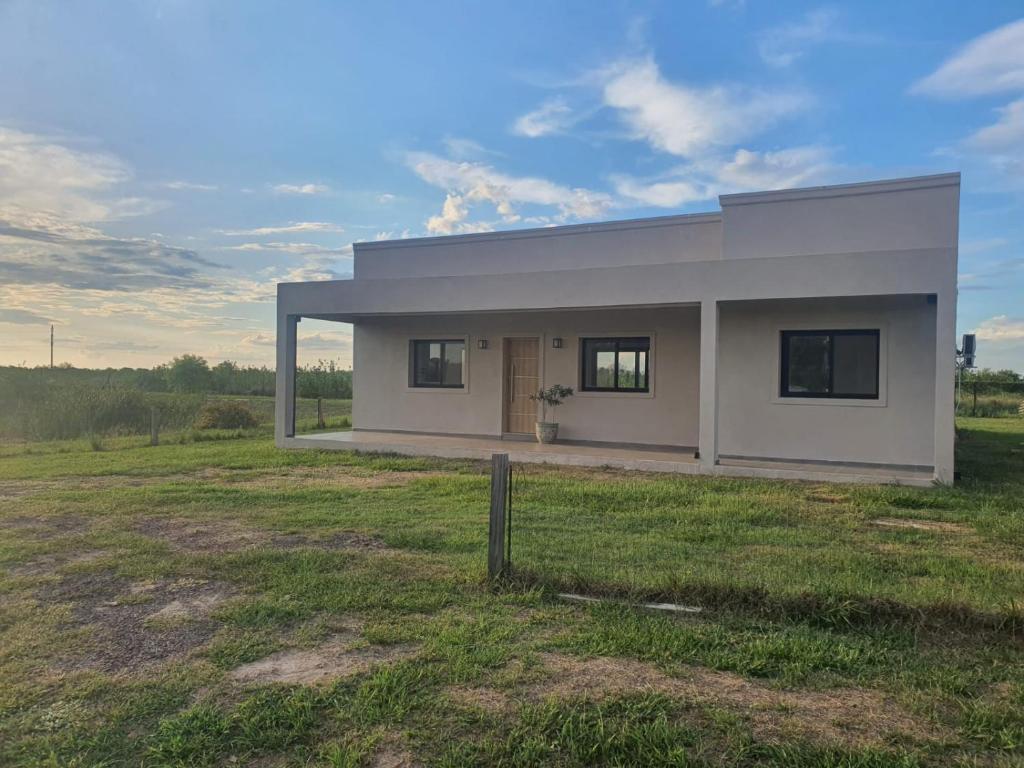 une petite maison blanche dans un champ herbeux dans l'établissement Casa en Laguna Soto Sur, à Corrientes