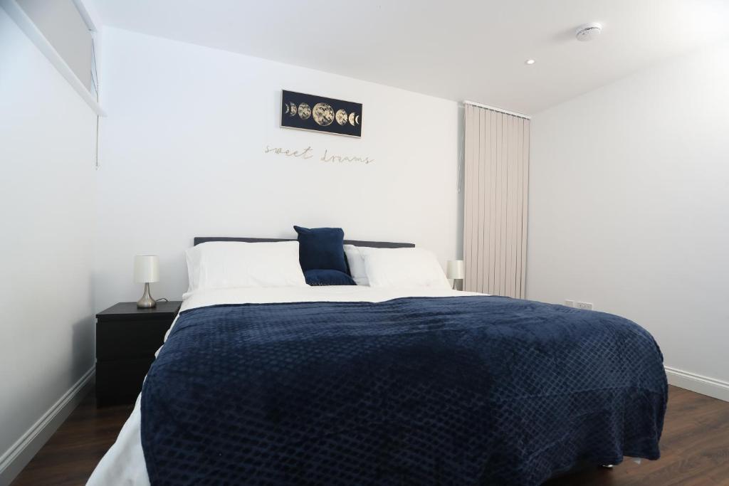 - une chambre avec un grand lit et une couette bleue dans l'établissement Central Watford Apartment, à Watford