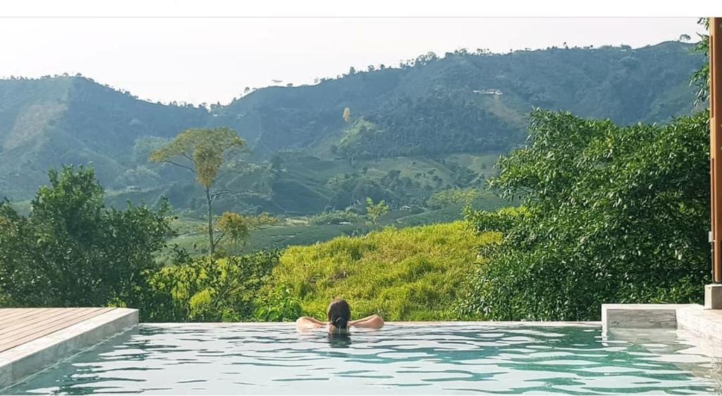 a person swimming in a pool with mountains in the background at Hotel Spa La Colina in Pereira
