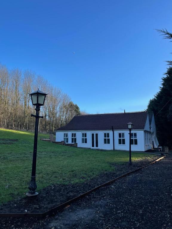 una casa bianca con un lampione davanti di Upsall Warren Cottage a Middlesbrough