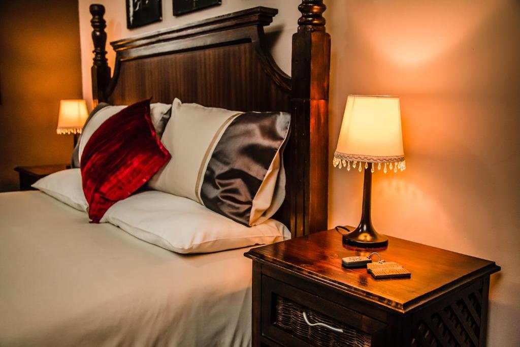ein Schlafzimmer mit einem Bett mit einer Lampe und einem Tisch in der Unterkunft Butlers Crown in Klerksdorp