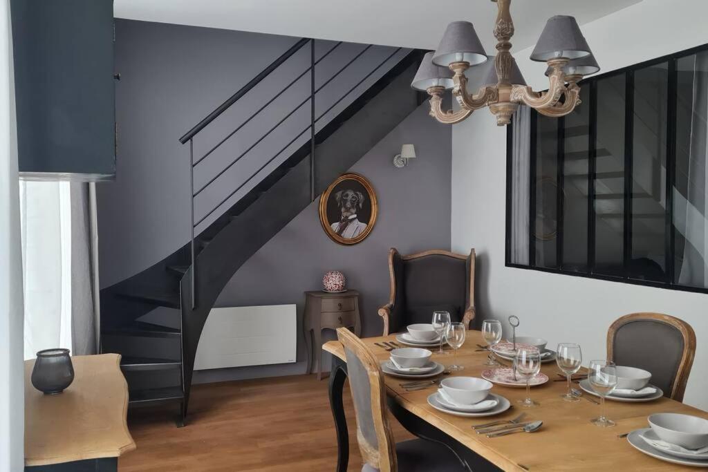 une salle à manger avec une table, des chaises et un escalier dans l'établissement Spacieux duplex en plein centre-ville de Fontainebleau, à Fontainebleau