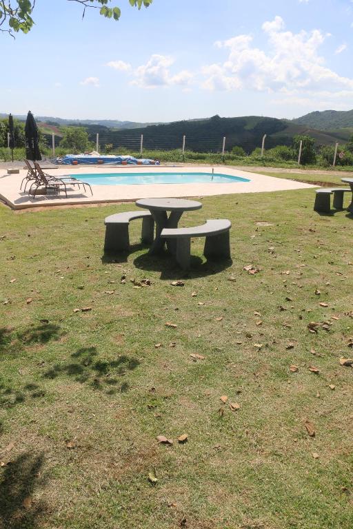 un gruppo di tavoli da picnic di fronte a una piscina di Sítio Terra Sertaneja - Chalé Um Sonhador a Piedade