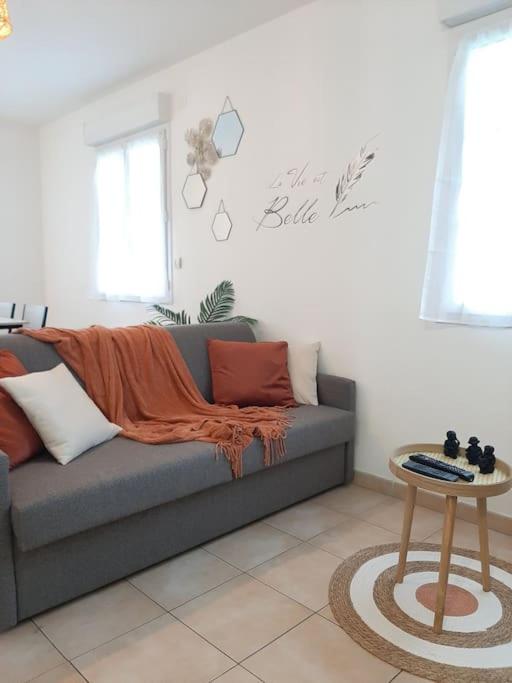 a living room with a couch and a table at Proche aéroport à pied, O Nature in Tillé