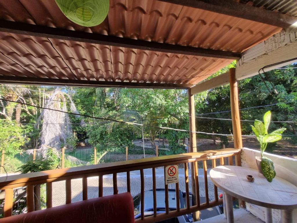 a porch with a table and a view of trees at Jurema Camping in Itacaré