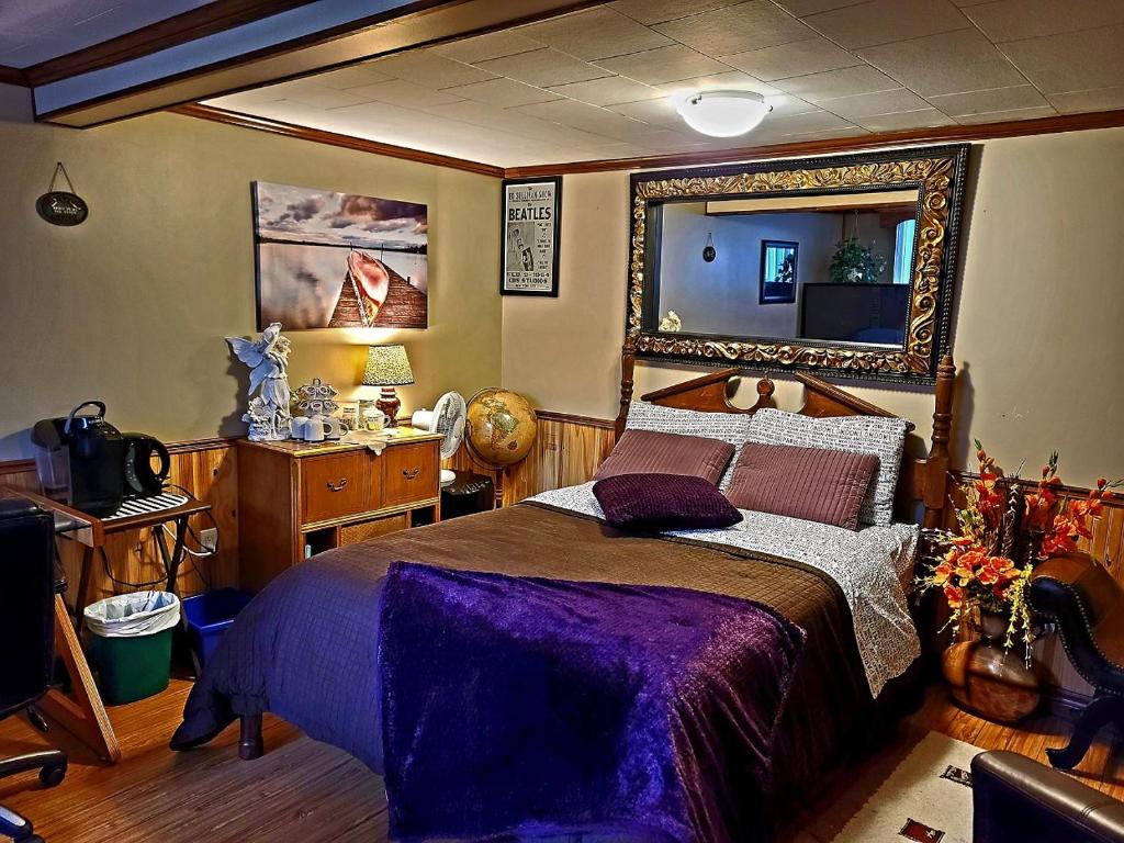 ein Schlafzimmer mit einem großen Bett und einem Spiegel in der Unterkunft Gîte du passant SADM, parc de la Gaspésie. in Sainte-Anne-des-Monts