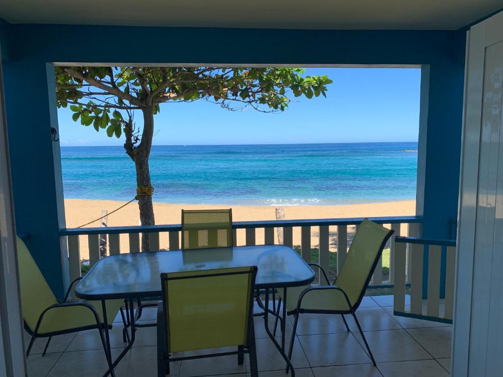 uma mesa e cadeiras numa varanda com vista para a praia em Parador Villas Del Mar Hau em Isabela