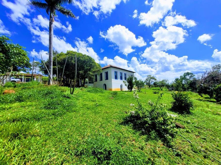 ein Haus auf einem grasbewachsenen Hügel mit einer Palme in der Unterkunft Fazenda centenária no Sul de MG 