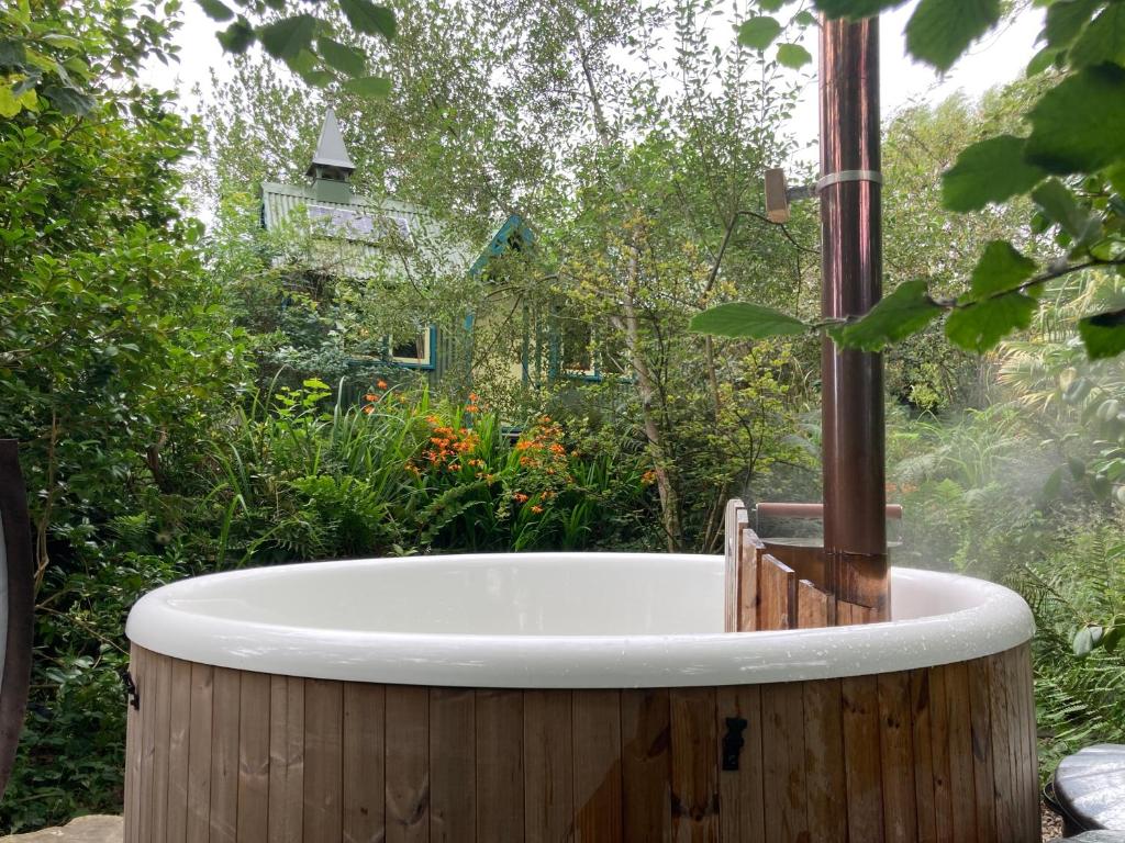 a bath tub in a yard with a garden at Enchanting Hand Painted Tabernacle with Hot Tub in Bude