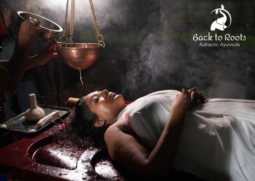 a woman laying on a bed in a bath room at Back to Roots Ayurveda Retreat in Kizhake Chālakudi