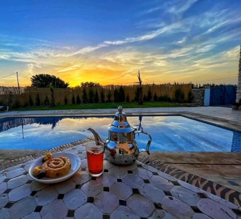 einen Wasserkocher und einen Teller mit Essen neben dem Pool in der Unterkunft Oasis Villa Essaouira in Essaouira