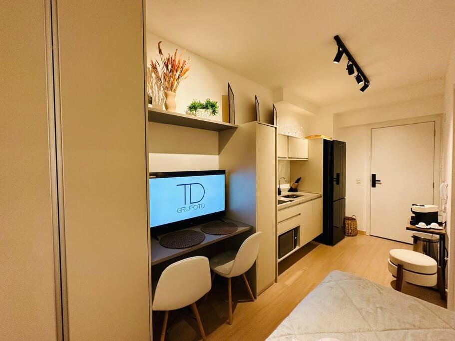 um quarto com uma cozinha com uma televisão e cadeiras em Apto novo NEX ONE 709 próximo a Av Paulista em São Paulo