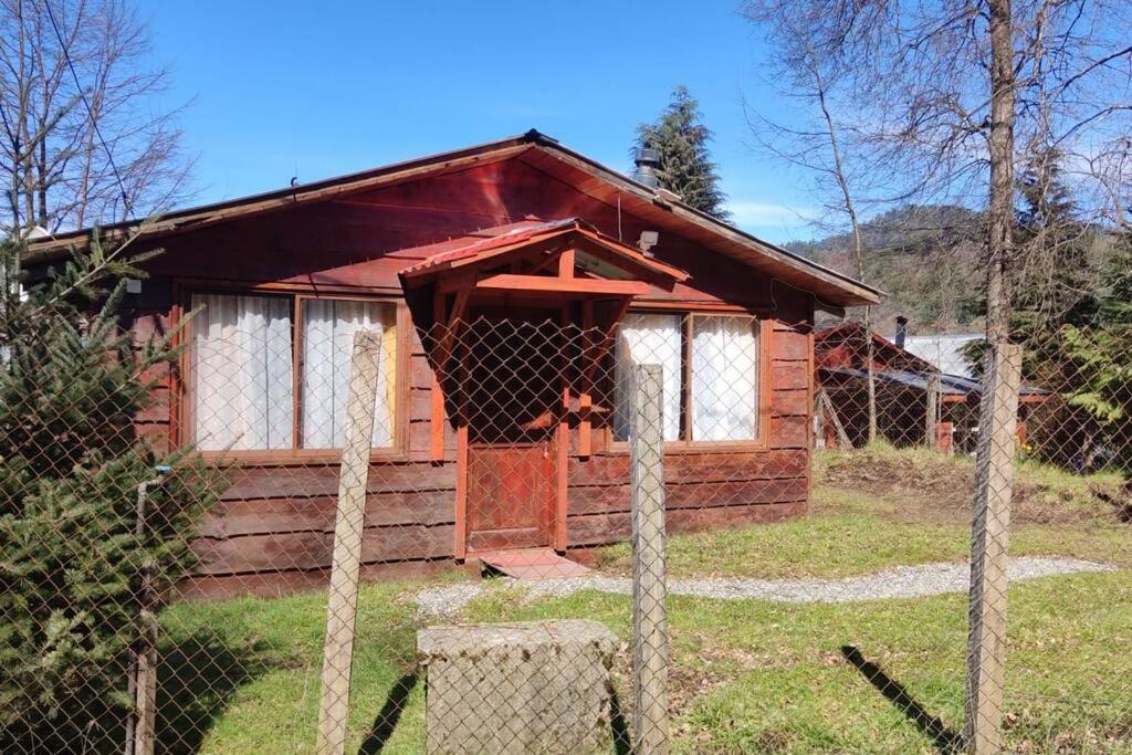 uma pequena cabana de madeira com uma cerca em frente em Cabaña Rustica, Lago/bosque/Puerto/Estufa Pellet em Puerto Fuy