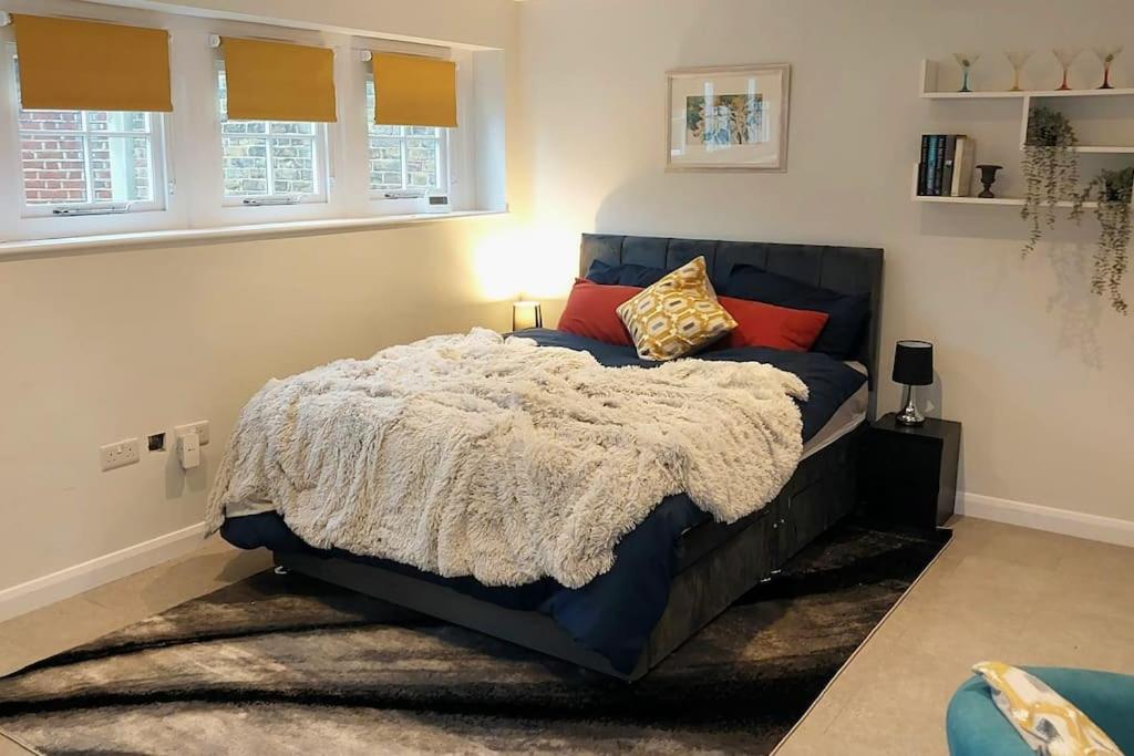 a bedroom with a large bed with red pillows at Turing Lodge, near Hampton Court in Hampton Hill