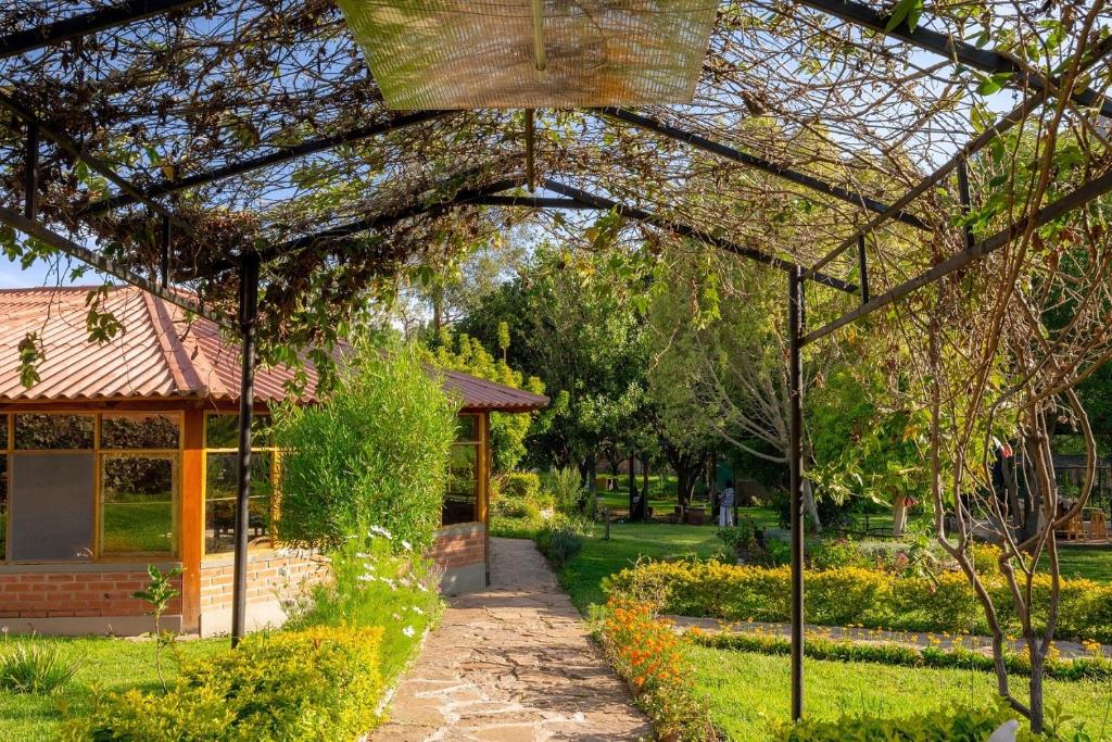 un jardin avec une pergola et une maison dans l'établissement Villa Etelvina, à Torotoro