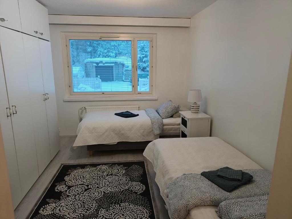 a small room with two beds and a window at Suuri huoneisto isommalle ryhmälle / Large apartment for bigger group in Tampere