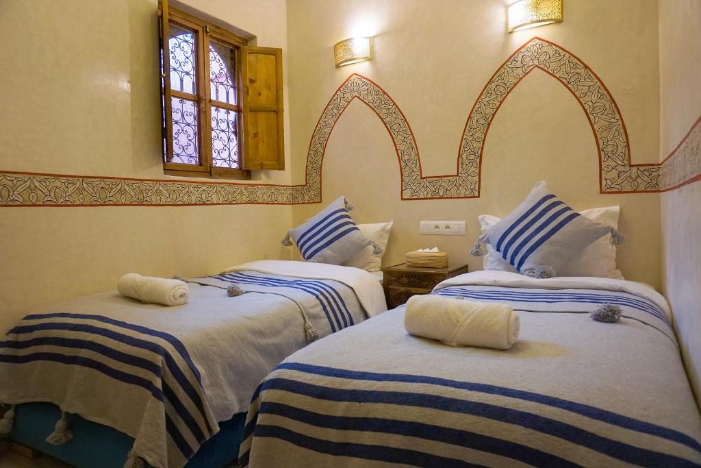 - une chambre avec 2 lits avec des draps bleus et blancs dans l'établissement Flowers riad, à Marrakech