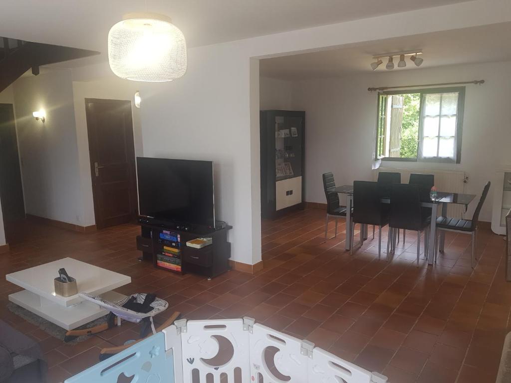 a living room with a television and a table and chairs at VILLA avec piscine sauna barbecue ping-pong boxe - proche Gare RER - JO Paris 2024 Olympic Games in Combs-la-Ville