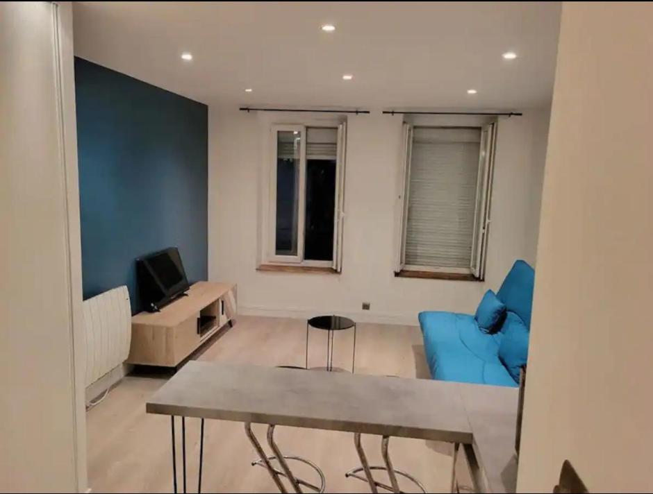 een woonkamer met een tafel en blauwe stoelen bij Studio Émeraude au centre-ville in Villejuif
