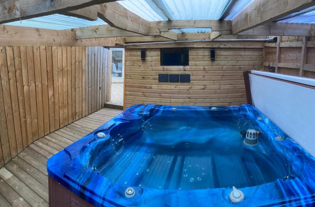 uma grande banheira azul num quarto com piso em madeira em Winnie Cottage - Hot Tub, Games Room, Sauna, Large Garden em Stocksfield