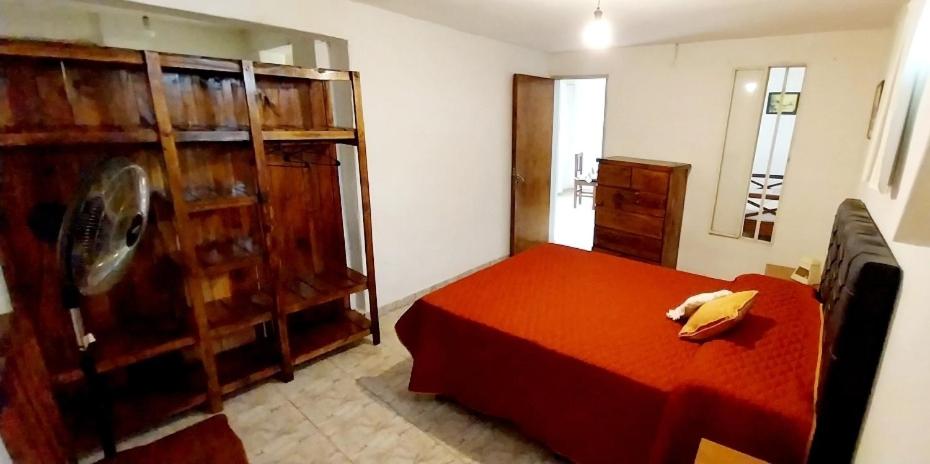 1 dormitorio con cama roja y armarios de madera en Lo de Liliana 1 in 