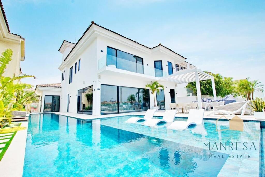 eine Villa mit einem Pool vor einem Haus in der Unterkunft ULTRA Modern Villa Manresa with Private Beach & Infinity Pool on Palm Island in Dubai