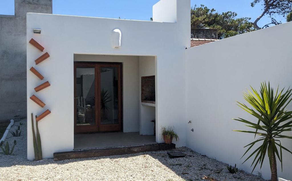 a white house with a wooden door and a plant at Casa Raices in Quequén