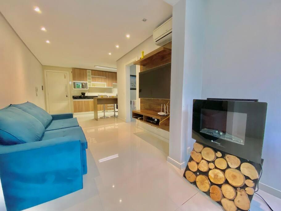 uma sala de estar com um sofá azul e uma televisão de ecrã plano em Apartamento com fácil acesso ao Vale dos Vinhedos em Bento Gonçalves