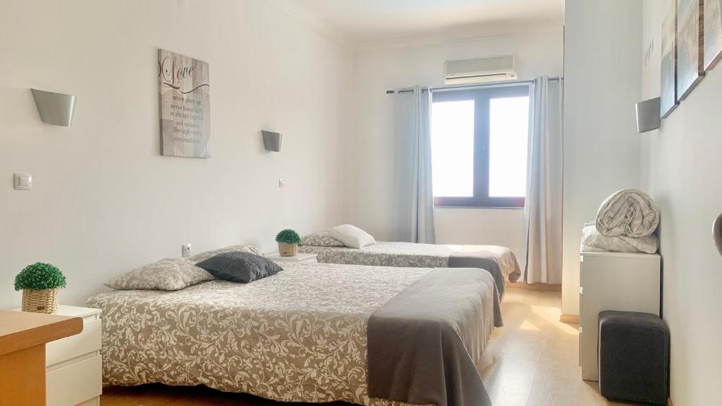2 camas en una habitación blanca con ventana en Sun Dreams Ericeira Apartment, en Ericeira
