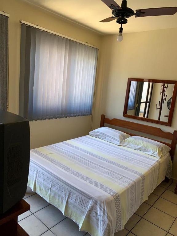 a bedroom with a bed with a ceiling fan and a television at APTO PRAIA DO MORRO, 02 QUARTOS C SUITE, WI-FI, GARAGEM, 1 ANDAR ESCADA. in Guarapari