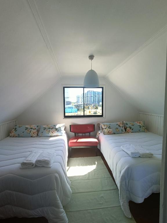 a attic room with three beds and a window at Casa Huésped Los Pablos in Temuco