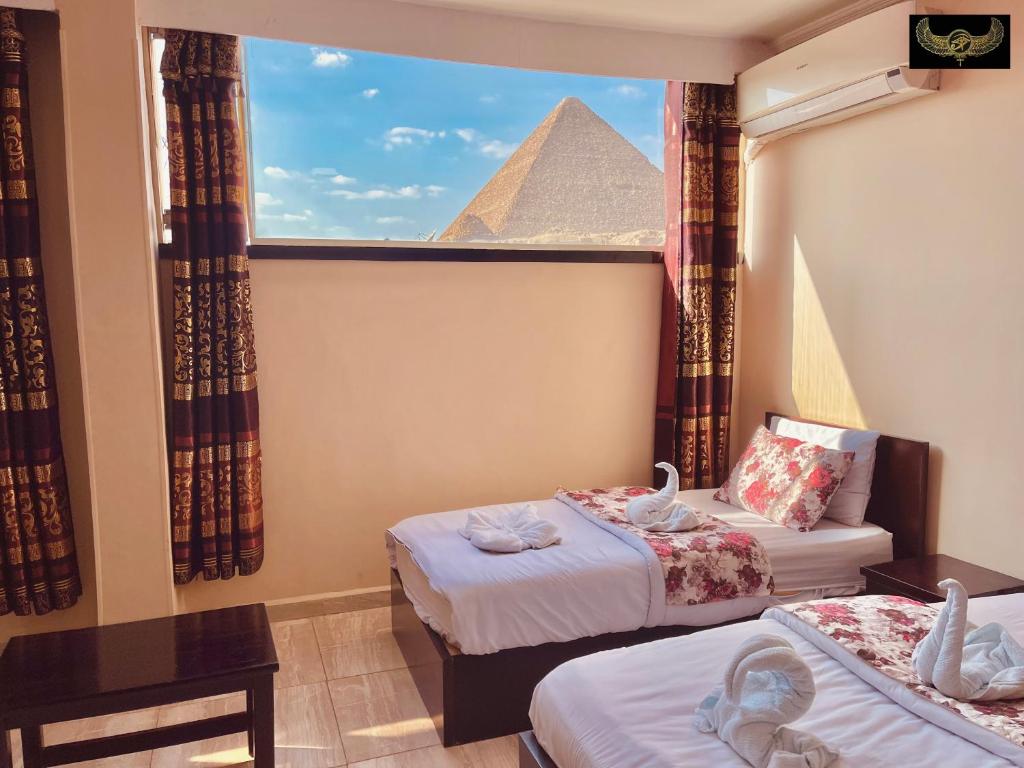 a room with two beds and a pyramid in the window at Comfort Pyramids&Sphinx Inn in Cairo