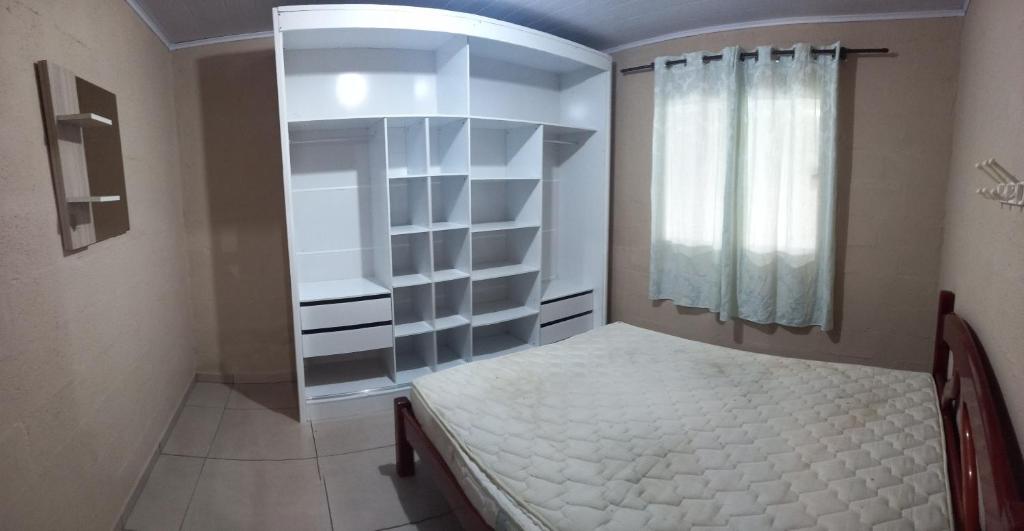 una piccola camera da letto con un letto e una finestra di Casa de praia a Palhoça