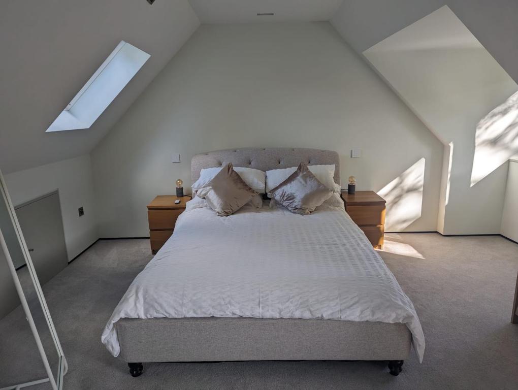 um quarto com uma cama com lençóis brancos e almofadas em The Nest at Fairfield em Wargrave