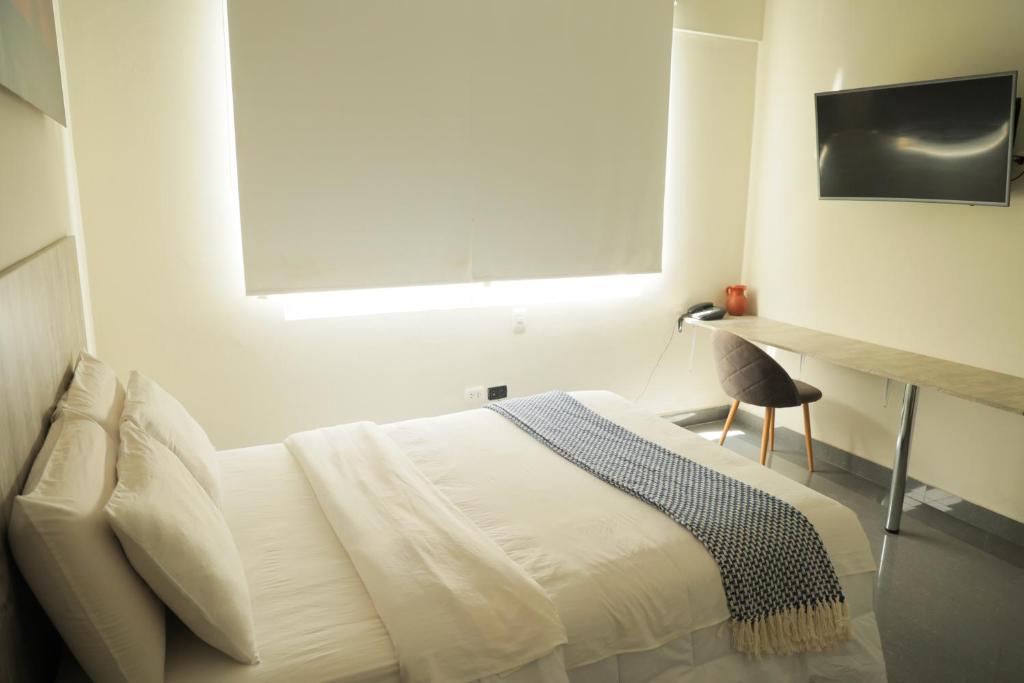 um quarto branco com uma cama e uma janela em Slim HOTEL em Piura