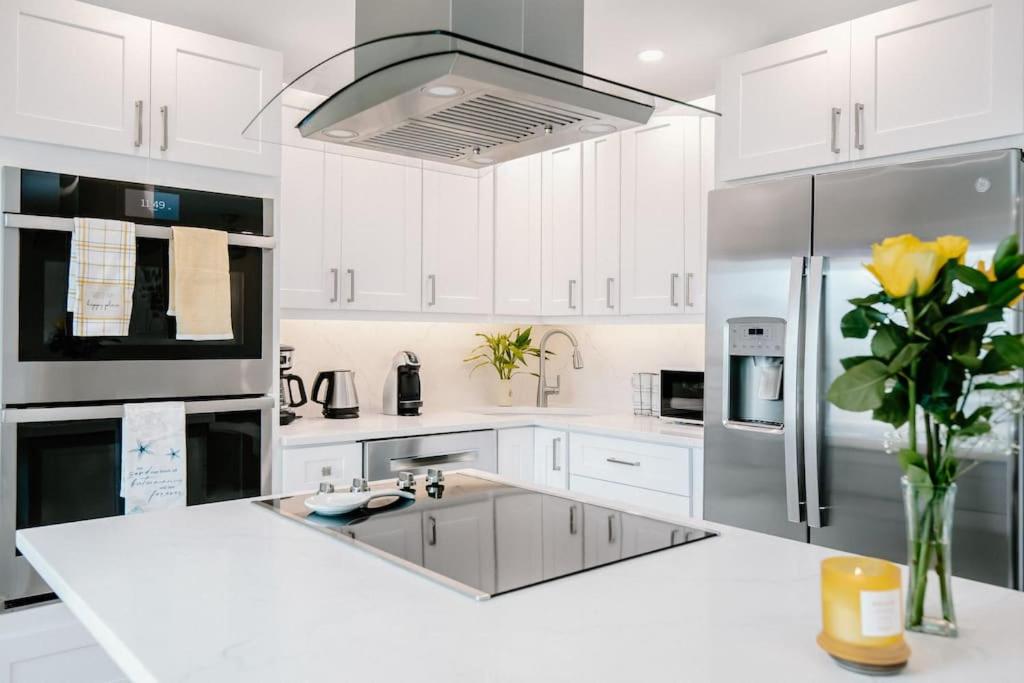 a kitchen with white cabinets and a stainless steel refrigerator at Seahorse Cottage - Pool Home in Naples