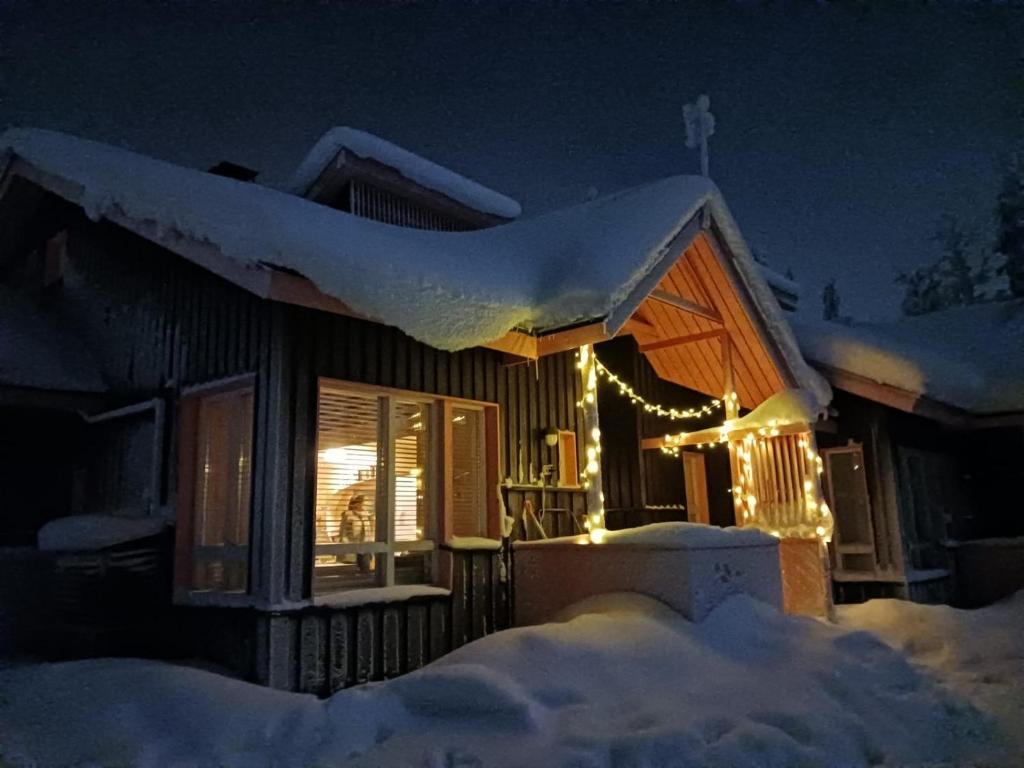 a house covered in snow at night with lights at Luttotupa in Saariselka