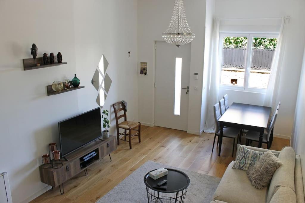 ein Wohnzimmer mit einem Sofa, einem TV und einem Tisch in der Unterkunft Maison 85m2- 10min de Paris Centre - Ideal Olympics in Houilles