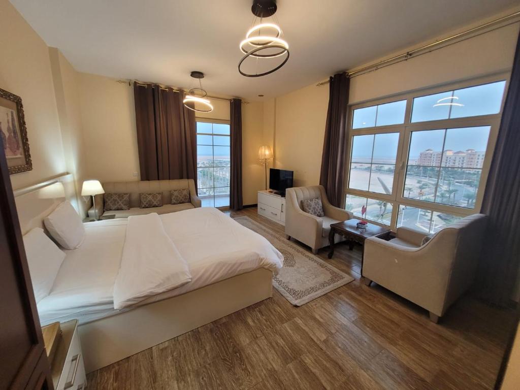 a bedroom with a large bed and a couch and chairs at Lotus Apartments in King Abdullah Economic City