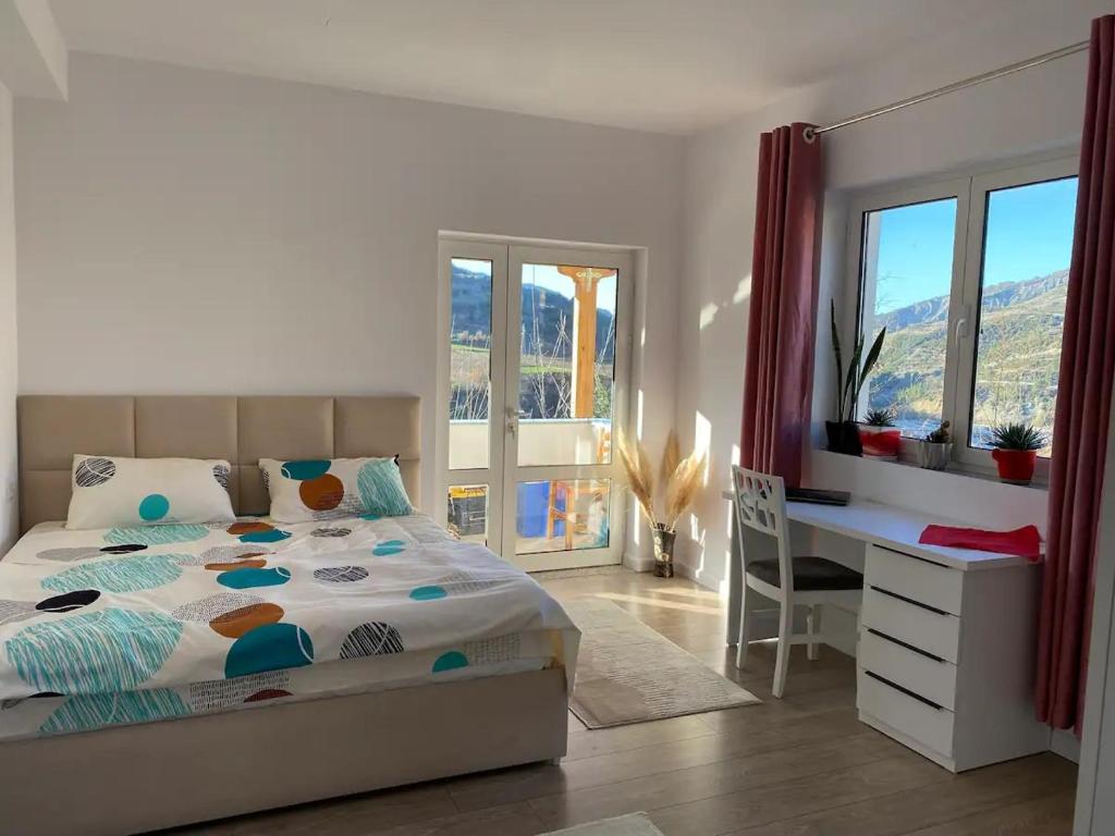 a bedroom with a bed and a desk and windows at Großes und schönes Zimmer mit Balkon in Çorovodë