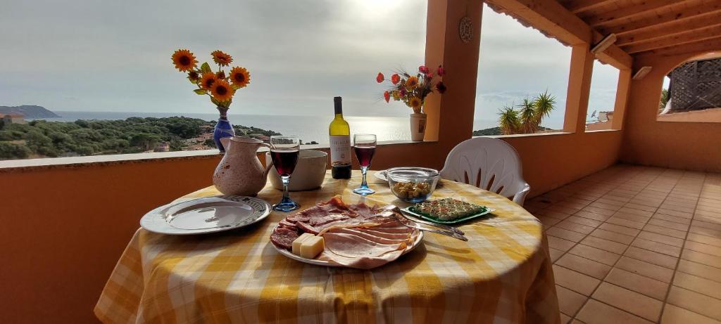 una mesa con un plato de comida y copas de vino en Casa Rosa Mari Pintau, en Geremèas