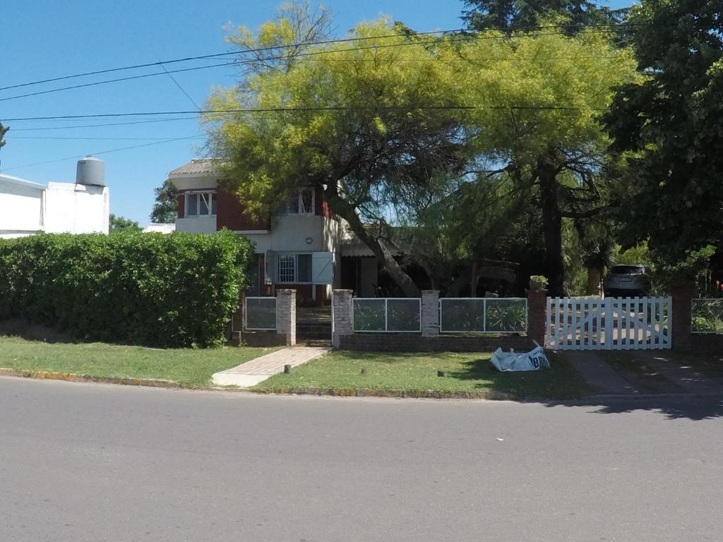 a fence in front of a house with a tree at San Miguel del monte 6 personas con pileta in San Miguel del Monte