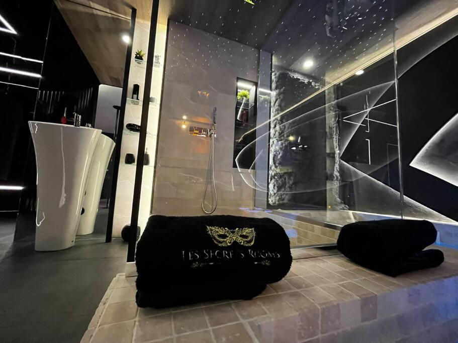 a bathroom with a shower and a black bag on the floor at Les Secrets Rooms/Love Room in Rivesaltes