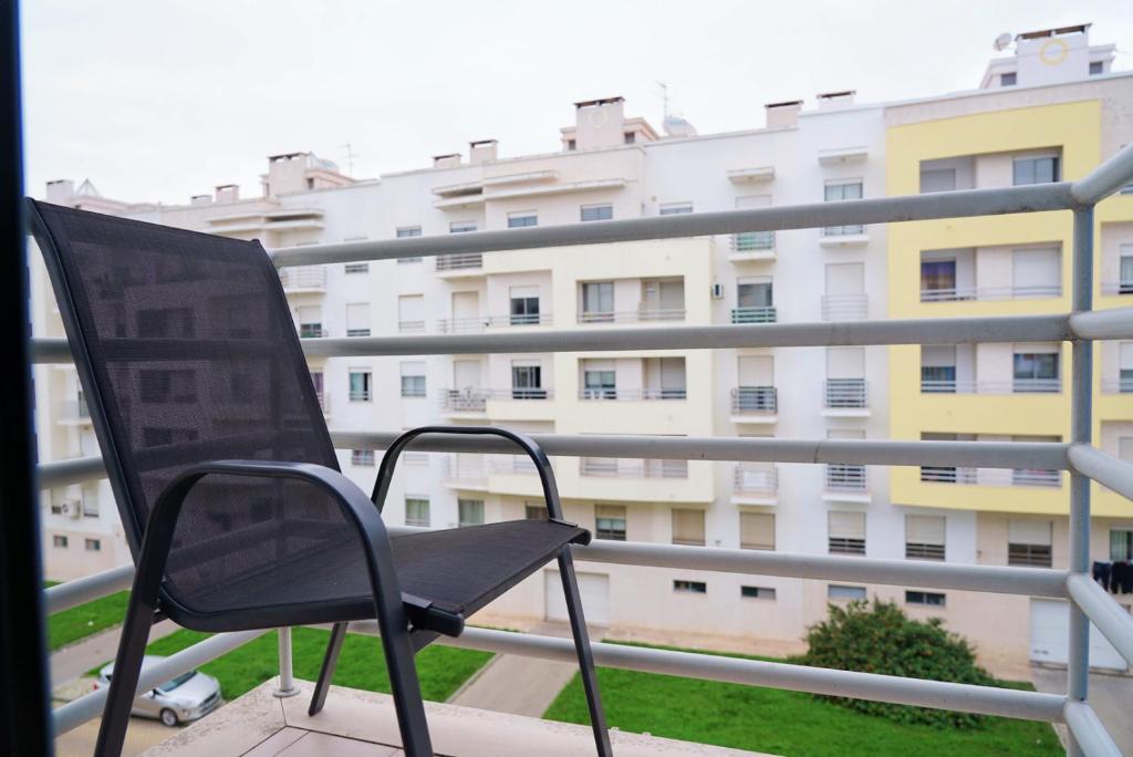 a black chair sitting on a balcony with a building at Always on the way - Road Home in Montijo, Lisbon in Montijo