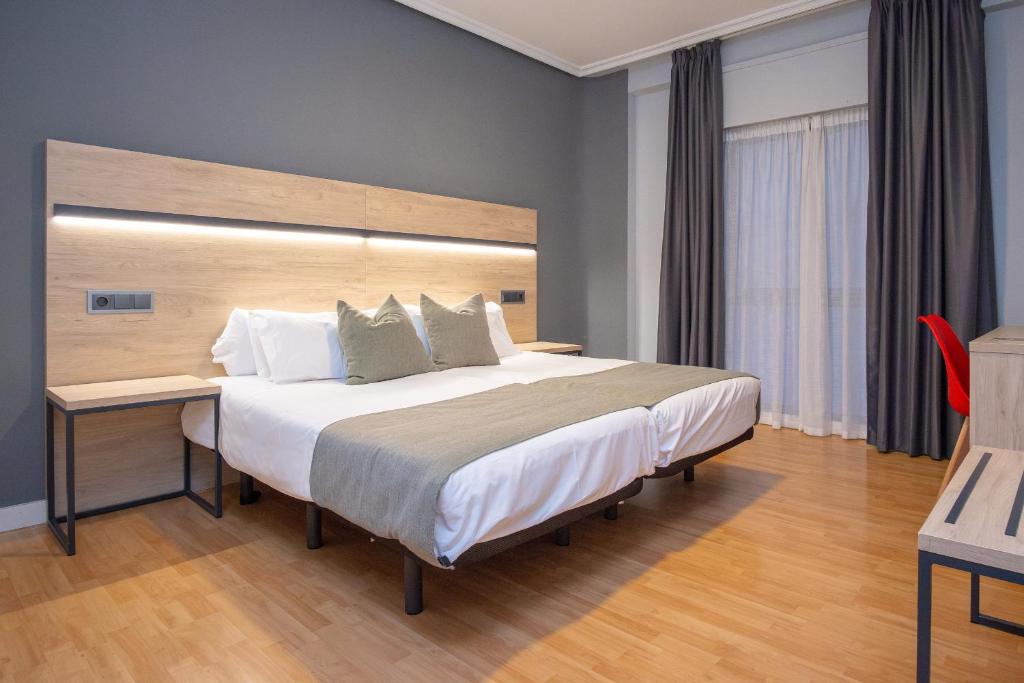 een slaapkamer met een groot bed met een houten hoofdeinde bij AZ Hotel El Príncipe in Zaragoza