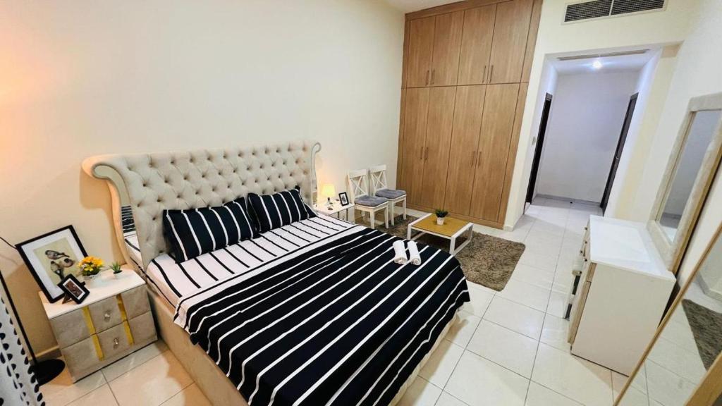 a bedroom with a large bed with a black and white striped blanket at Master Room with attach Bathroom Near Mall of the Emirates in Dubai