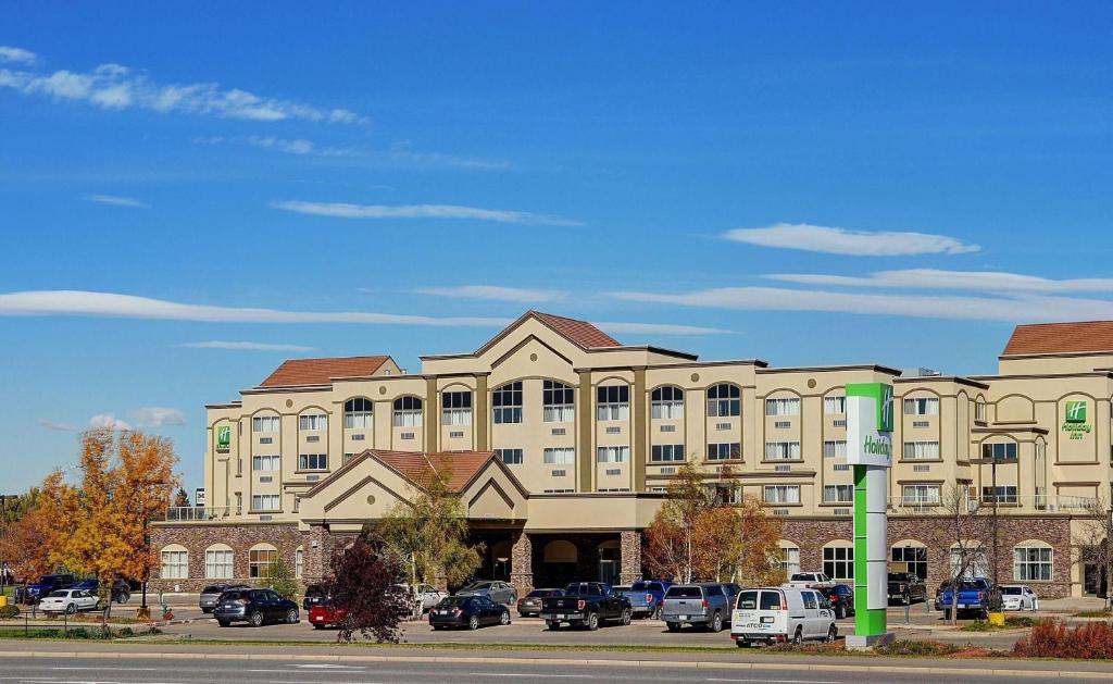 Holiday Inn Lethbridge, an IHG Hotel في ليثبريدج: مبنى كبير به سيارات تقف في موقف للسيارات